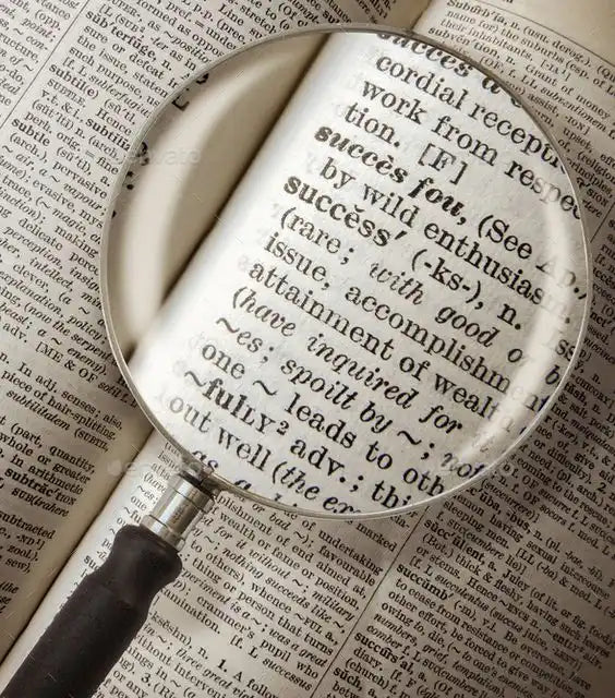 Magnifying glass positioned over dictionary text.